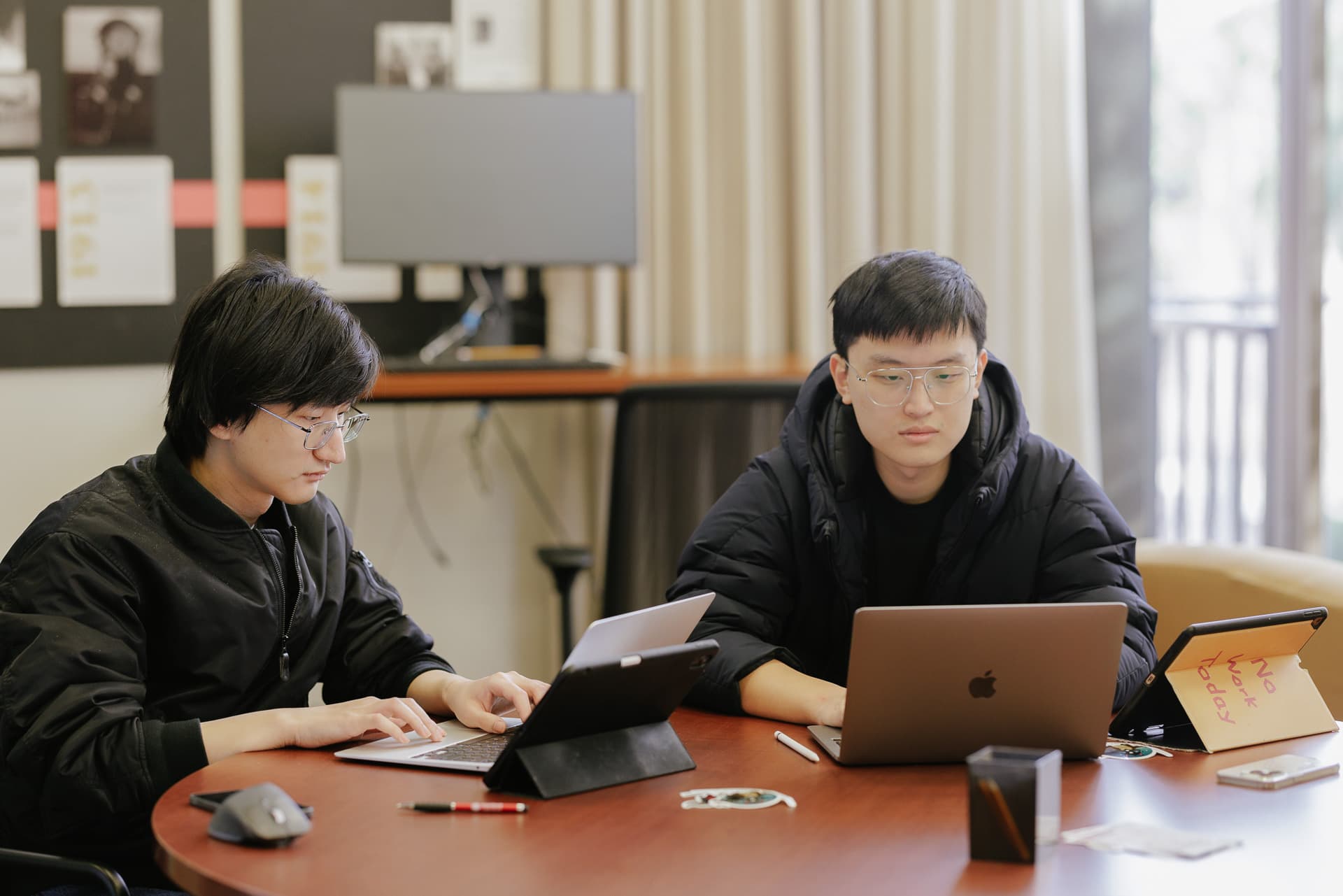 Students using laptops in seating area near the windows