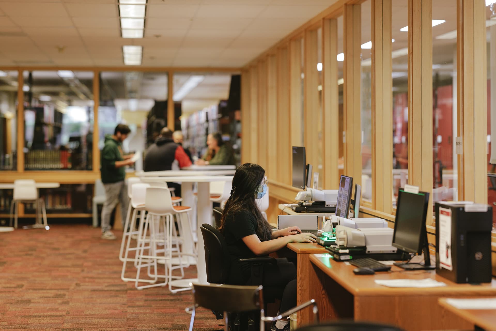 Student using microfilm reader and other students studying